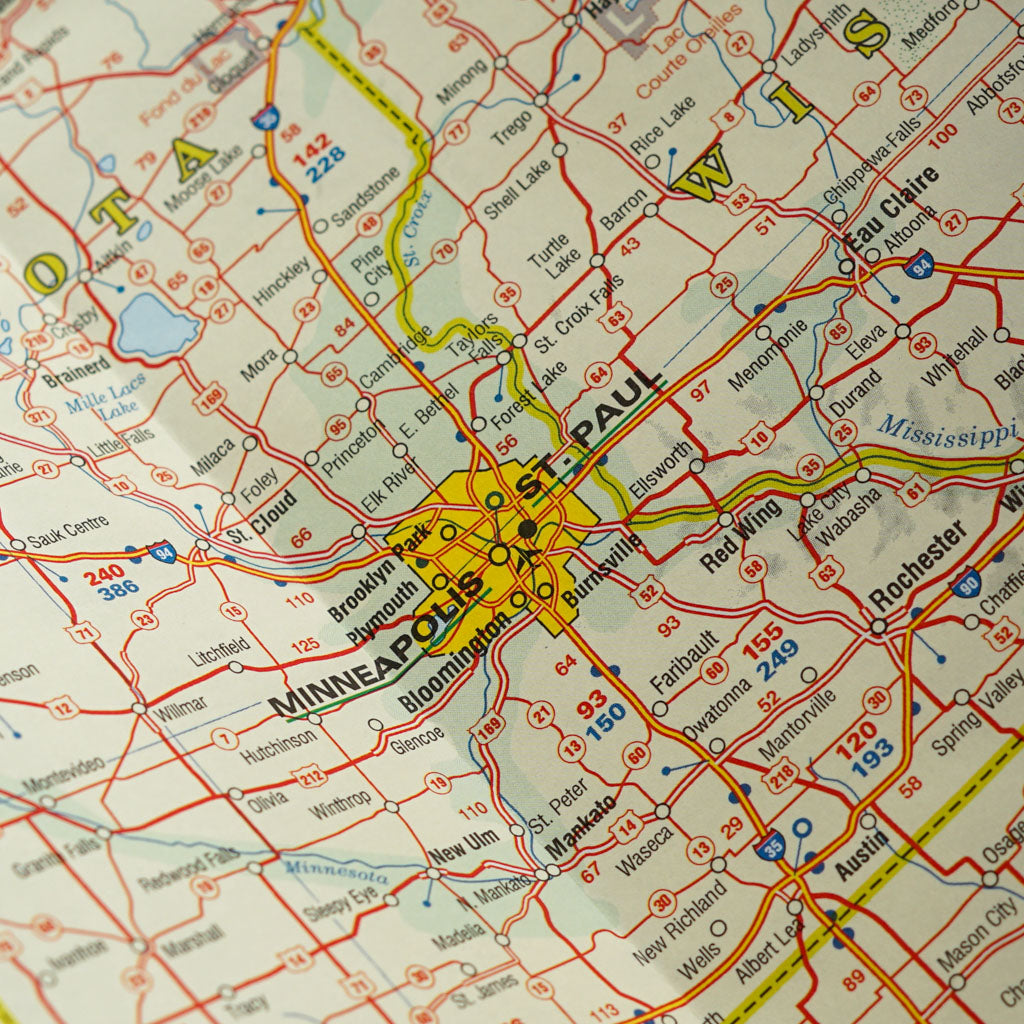 Close-up of a road map showing the cities of Minneapolis and St. Paul, Minnesota, with major highways and surrounding towns. Perfect for travel-related content or products for the Midwest United States.
